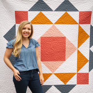 Paradigm Quilt Pattern (Download) by Homemade Emily Jane featuring a bold modern geometric quilt in coral orange navy and white beside a smiling woman