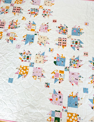 Close-up of a colorful quilt featuring geometric floral and heart patterns, showcasing the Paw Tracks Quilt Pattern (Download) by Lou Orth Designs on a white background.