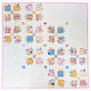 Paw Tracks Quilt Pattern (Download) by Lou Orth Designs, featuring a colorful modern quilt with floral and geometric prints on a white background with pink binding.