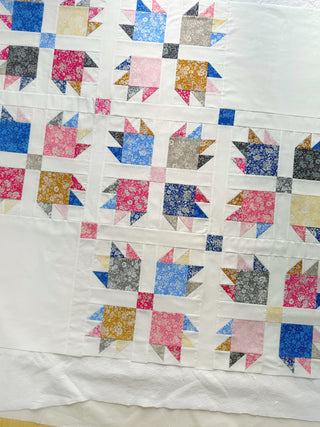 Close-up of a colorful Paw Tracks Quilt Pattern (Download) featuring floral fabric squares and triangles on a white background designed by Lou Orth Designs.