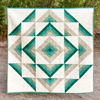 A geometric quilt featuring a diamond and triangular pattern in shades of teal and beige, showcasing the Percussion Quilt Pattern (Download) by Shadow Valley Quilts.