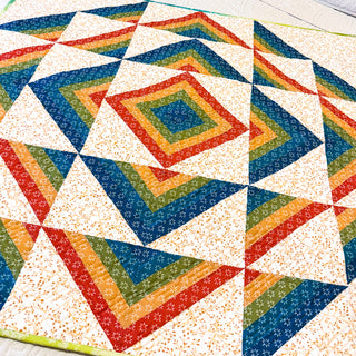 Colorful geometric quilt featuring vibrant rainbow stripes and floral patterns in a modern design, crafted by Shadow Valley Quilts using the Percussion Quilt Pattern (Download).