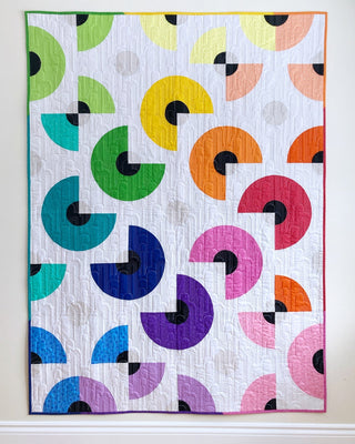 Colorful geometric quilt with curved piecing in bright hues on white background, showcasing the Pie in the Sky Quilt Pattern (Download) by Penny Spool Quilts.