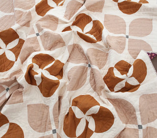 Quilt with brown and beige floral pattern on a white background