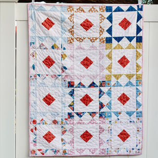 Reverberate Quilt Pattern (Download) by Homemade Emily Jane, a modern geometric quilt with colorful square blocks and red diamond accents.