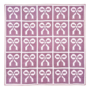 A quilt featuring a repeating white bow and ribbon block design on a pink background, showcasing the Ribbons & Bows Quilt Pattern (Download) by Sew & Sew Quilting Co.