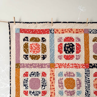 Close-up of a colorful quilt corner featuring intricate patchwork and quilting, created with the Saltbox Quilt Pattern (Download) by The Dandy Patch.