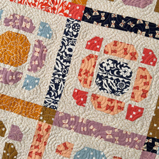 Close-up of a colorful quilt featuring intricate stitching and geometric patterns made with The Dandy Patch's Saltbox Quilt Pattern (Download).