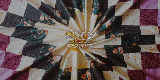 A close-up view of a folded quilt featuring a patchwork design with floral and solid colored squares in shades of cream, black, and burgundy with the Thai Charm logo.