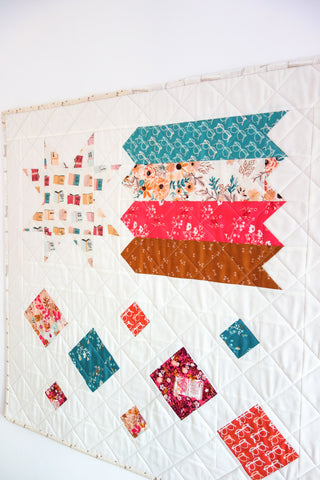 Quilt featuring colorful geometric star and flag shapes with floral and book patterns, showcasing the Shooting Stars Quilt Pattern (Download) by Lou Orth Designs.