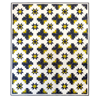 Modern quilt featuring yellow and blue geometric star and cross blocks on a white background, showcasing the Solstice Burst Quilt Pattern (Download) by A Piece of Quiet Quilts.