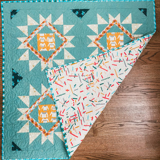Quilt showcasing the Splendid Shimmer Quilt Pattern (Download) by A Piece of Quiet Quilts, featuring teal and cream star blocks with colorful patchwork accents.