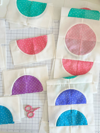Close-up of colorful quilt blocks with half circle shapes in blue, pink, purple, and teal polka dot patterns by Lou Orth Designs for Spring Moon Quilt Pattern (Download).