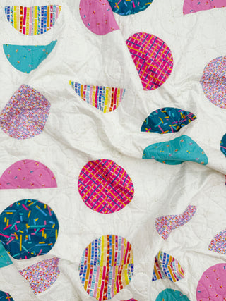 Close-up view of colorful geometric shapes quilted on white fabric showcasing Spring Moon Quilt Pattern (Download) by Lou Orth Designs with modern quilting style.