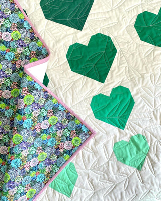 Quilt with green heart shapes on a white background
