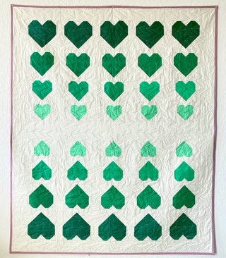 Quilt with green heart patterns on a white background