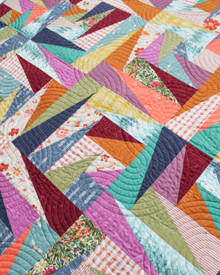 Colorful geometric quilt blocks with diverse fabric patterns and intricate circular quilting stitches, showcasing the Super Scrappy Repair Quilt Pattern (Download) by Eudaimonia Studio.
