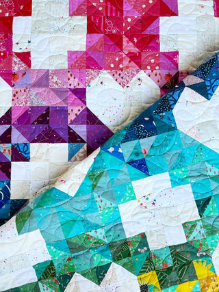 Close-up of colorful quilt blocks in shades of pink, purple, blue, and green with intricate patterns and stitching, showcasing Sweet Darlings Quilt Pattern (Download) by Lou Orth Designs.