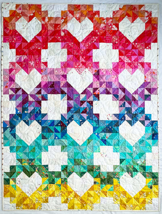 Colorful quilt with heart and geometric patterns in vibrant red, pink, purple, blue, teal, green, and yellow shades, made using the Sweet Darlings Quilt Pattern (Download) by Lou Orth Designs.