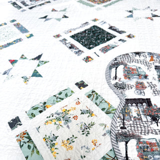 Timber & Glow Quilt Pattern by Sew & Sew Quilting Co. flat lay closeup: cream quilt with green, teal, and colorful floral patterned fabric diamond star blocks.