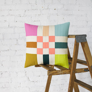 Colorful modern quilted pillow showcasing the To The Nines Quilt Pattern (Download) by Patternly Collective with geometric blocks in pink, blue, green, and gold tones.