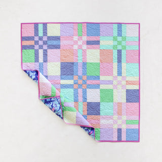 Colorful pastel patchwork quilt with a geometric plaid design and a floral backing, showcasing the To The Nines Quilt Pattern (Download) by Patternly Collective.