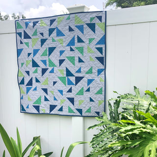Triangular Quilt Pattern (Download) by Homemade Emily Jane featuring dynamic blue green and white geometric triangle shapes on a modern quilt hanging outdoors