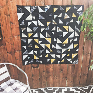 Triangular Quilt Pattern (Download) by Homemade Emily Jane featuring a modern geometric quilt with black white gray and yellow triangle shapes on a wood wall