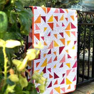 Triangular Quilt Pattern (Download) by Homemade Emily Jane featuring a modern geometric quilt with colorful triangle shapes in red yellow pink and orange tones