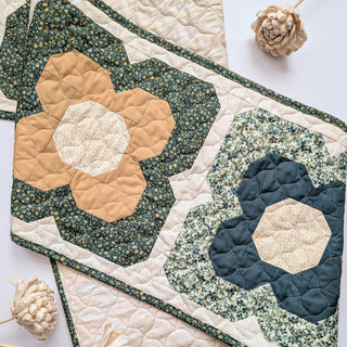 Close-up of floral patchwork quilted table runner in muted green, beige, and mustard colors with detailed stitching, showcasing Trula's Blooms Table Runner Quilt Pattern (Download) by Heart Lake Quilts