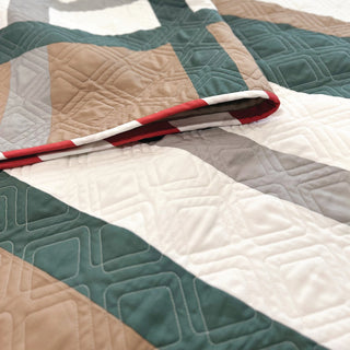Closeup of a modern quilt with geometric stitching in green, beige, white, and gray tones, showing the detailed quilting of the Urban Pine Quilt Pattern (Download) by Sew & Sew Quilting Co.