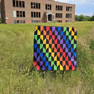 Vibrant Quilt Pattern by Staci W Quilts cover: rainbow-colored diamond block quilt displayed outdoors in front of a brick building.