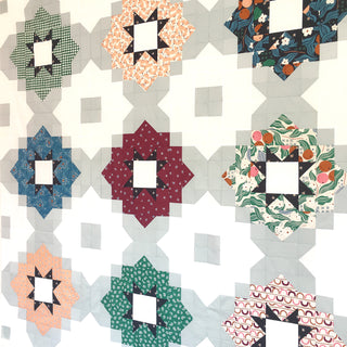 Close-up of a colorful quilt made with varied patterned fabrics showcasing the Vintage Tiles Quilt Pattern (Download) by Lou Orth Designs with a modern geometric style.