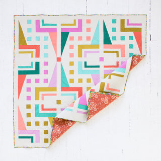 Colorful geometric patterned quilt on a white wooden surface