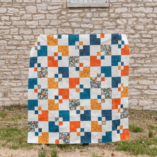 Welcome Party quilt by Trace Creek Quilting against a stone wall