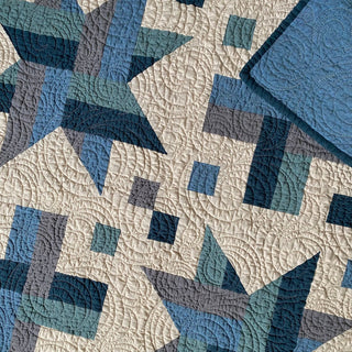 Closeup of a blue, teal, and gray quilt with intricate circular quilting patterns, showcasing the Wink Quilt Pattern (Download) by The Dandy Patch.