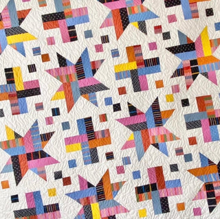Close-up of a colorful quilt featuring star and cross block patterns with intricate quilting details, showcasing the Wink Quilt Pattern (Download) by The Dandy Patch.