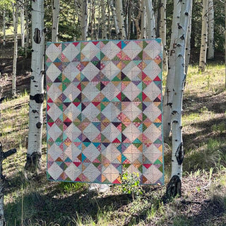 Amazing Grace Quilt Pattern (Download) by The Gluten Free Quilter featuring a colorful geometric quilt with interlocking diamonds and rhythmic pinwheels outdoors