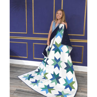 Beaming Quilt Pattern (Download) by Homemade Emily Jane featuring a bright modern star quilt with teal blue and green geometric blocks displayed as a draped throw
