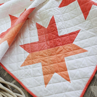 Beaming Quilt Pattern (Download) by Homemade Emily Jane featuring a bright red orange and white geometric star quilt design with modern quilting details