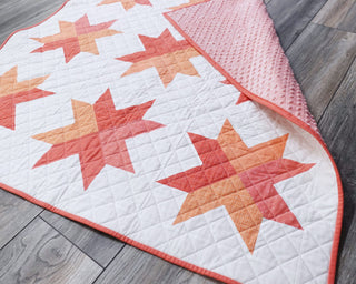 Beaming Quilt Pattern (Download) by Homemade Emily Jane featuring coral and peach star quilt blocks on a white quilt with playful geometric contrast
