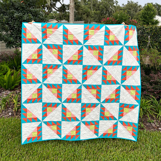 Brazen Quilt Pattern (Download) by Homemade Emily Jane featuring bold geometric quilt blocks in turquoise coral yellow and white displayed outdoors