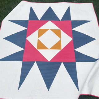 Catalyst Quilt Pattern (Download) by Homemade Emily Jane featuring a modern geometric quilt with navy star points pink center and gold diamond accents on white