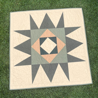 Catalyst Quilt Pattern (Download) by Homemade Emily Jane featuring a modern geometric star quilt in cream gray and peach on grass
