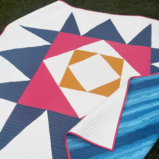 Catalyst Quilt Pattern (Download) by Homemade Emily Jane featuring a modern geometric quilt in white navy pink and mustard with bold angular shapes layered over blue stripes