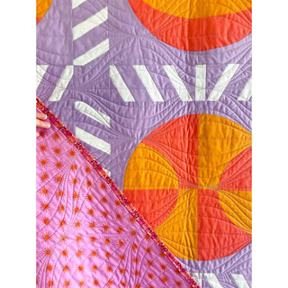 Nothin' But Net Quilt Pattern (Download) by Jessica Steele Design featuring colorful basketball blocks and strip pieced sashing in purple orange and pink quilted fabric