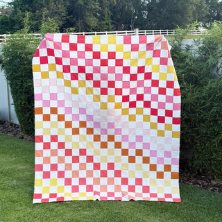 Doubled Up Quilt Pattern (Download) by Homemade Emily Jane featuring a colorful geometric checkerboard quilt with layered pink red yellow and orange squares outdoors
