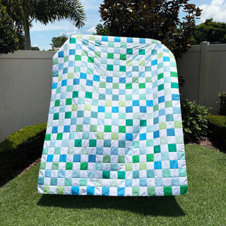 Doubled Up Quilt Pattern (Download) by Homemade Emily Jane featuring a modern geometric quilt in blue green and white squares displayed outdoors