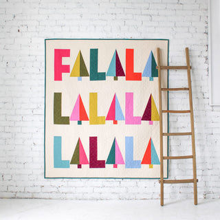 Fa-La-La Quilt Pattern (Download) by Patternly Collective featuring colorful geometric holiday lettering and stylized trees in a festive wall quilt design