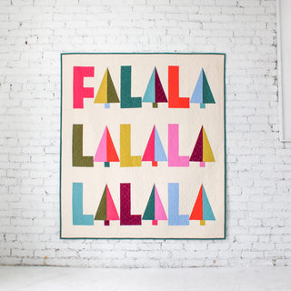 Fa-La-La Quilt Pattern (Download) by Patternly Collective featuring a colorful modern holiday quilt with repeated Fa La La lettering and geometric triangles